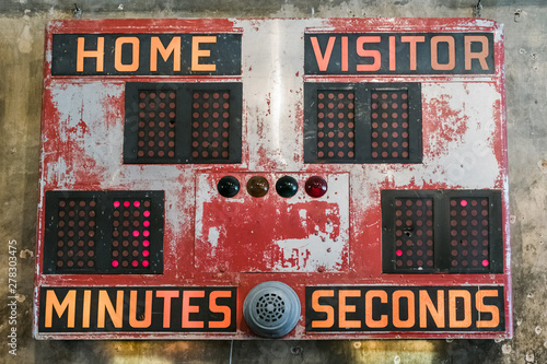 A rusty vintage scoreboard hanging on a wall.