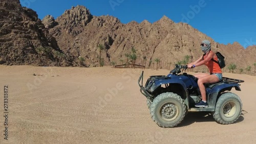 Sexy Woman is Riding a Quad Bike in the Desert of Egypt. Dynamic view in motion. photo