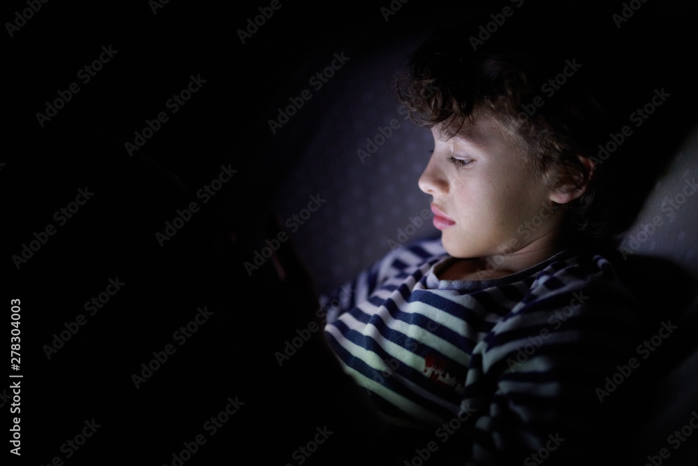 Little boy enjoying tablet in darkness Little boy enjoying tablet in darkness