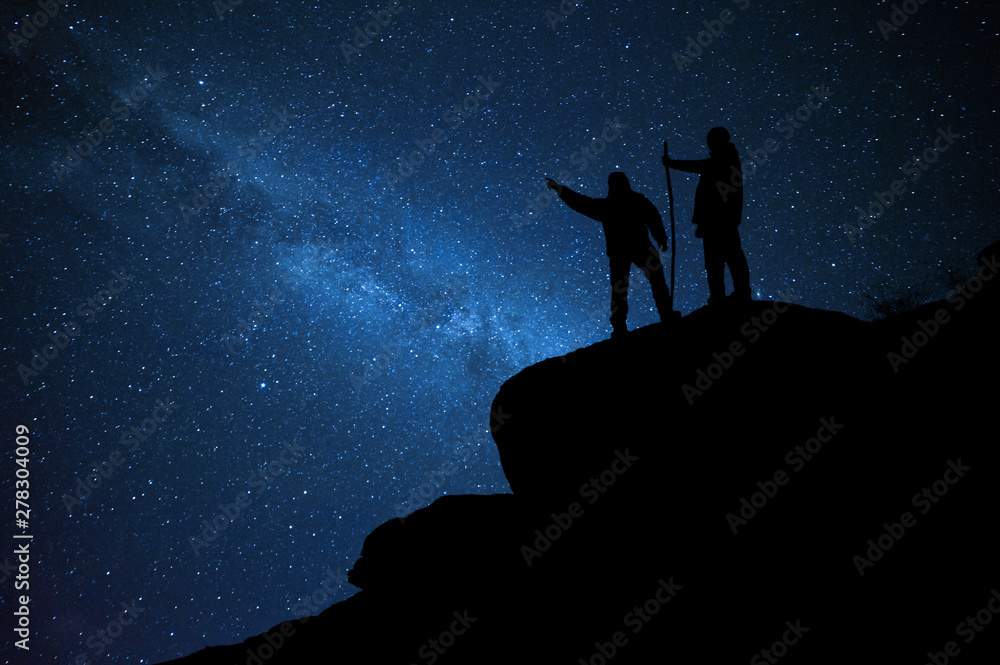 Mountaineers on rock enjoying view of night sky
