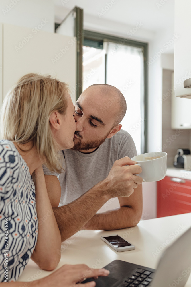 Adult Couple Using a Laptop From a Kitchen during the Morning Breakfast Adult Couple Using a Laptop From a Kitchen during the Morning Breakfast