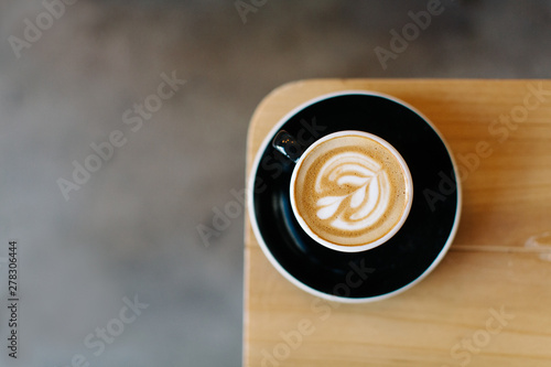 Cup of expresso sitting on the edge of a wooden table photo