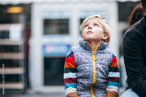 child looking up in awe at city skyscrapers photo