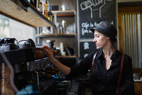 Young female barista preparing a espresso coffee photo