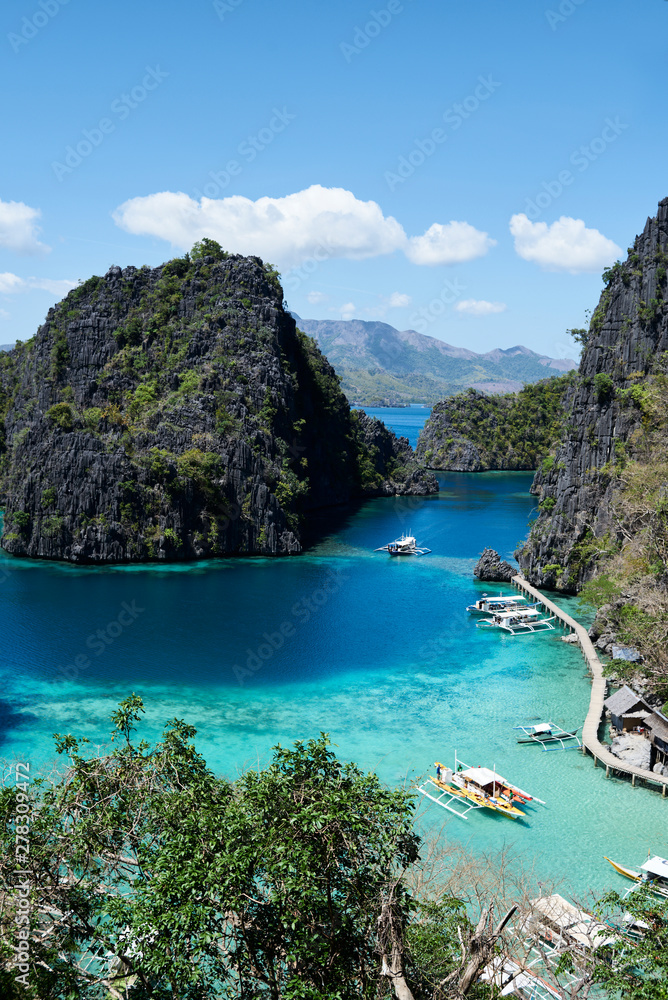 High view of paradise beach surrounded by rocks with traditional banka boats moored. High view of paradise beach surrounded by rocks with traditional banka boats moored.