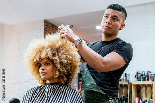 Beautiful afro woman getting haircut by hairdresser in the beauty salon photo