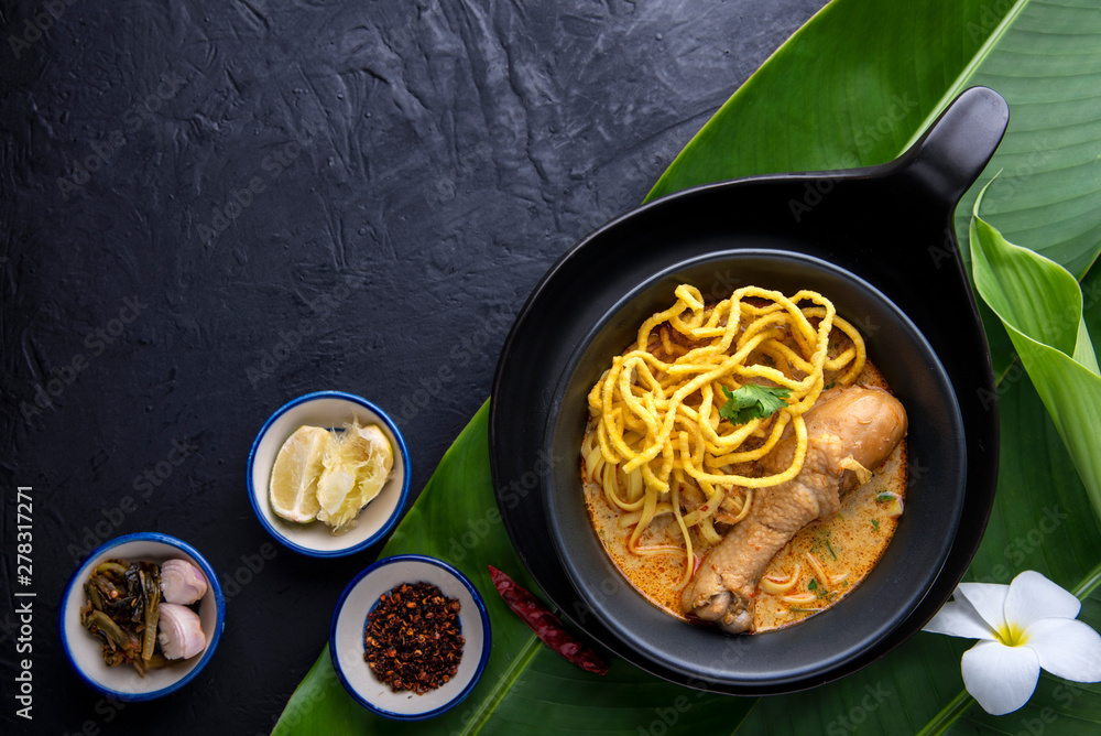 Thai noodle, Khao Soi Curried Noodle Soup with Chicken on dark background Thai noodle, Khao Soi Curried Noodle Soup with Chicken on dark background