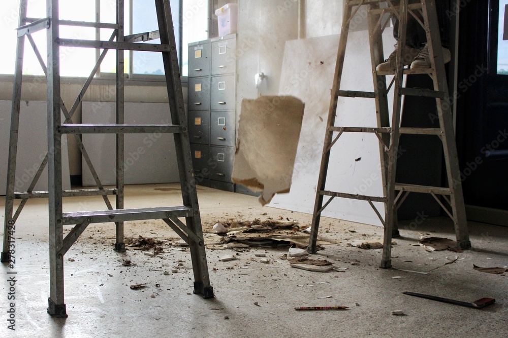 Aluminum ladders are on the floor and ceiling debris and large amounts of dust, blurred photographs