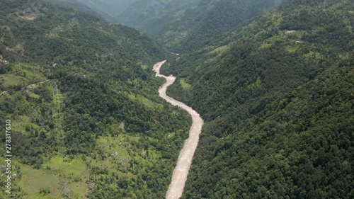 Aerial, tilt down, drone shot, above the Tista river, in a valley between mountains and Indian forest, on a sunny day, in Sikkim, India photo