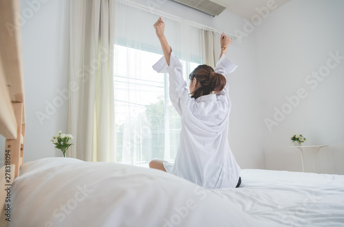 Back view Woman stretching on bed after wake up