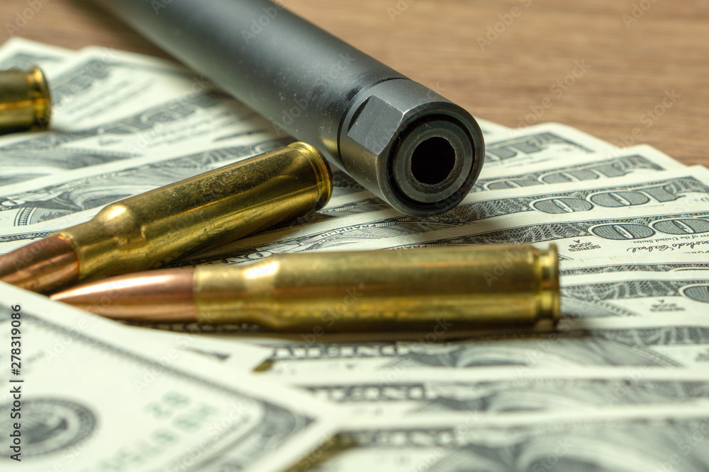 Rifle barrel, magazine and cartridges on money. Concept for crime, contract killing, paid assassin, terrorism, war, global arms trade, weapons sale. Illegal hunting, poaching Rifle barrel, magazine and cartridges on money. Concept for crime, contract killing, paid assassin, terrorism, war, global arms trade, weapons sale. Illegal hunting, poaching