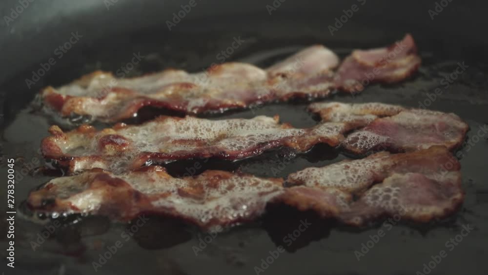 Crispy bacon strips fry in greasy fat in skillet, Slow Motion Close Up Crispy bacon strips fry in greasy fat in skillet, Slow Motion Close Up