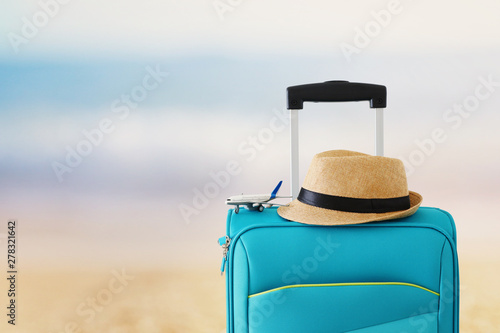 holidays. travel concept. blue suitcase and airplane toy infront of tropical sea background
