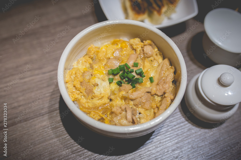 Japanes food gyudon or butadon with egg lunch meal on wood table Japanes food gyudon or butadon with egg lunch meal on wood table