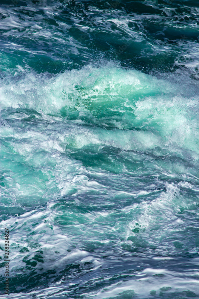 Aquatic background of sea surf waves splashing close up with clear blue green water and white foam