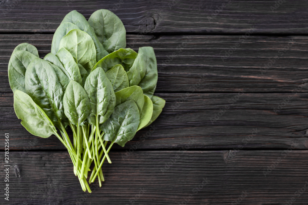 Fototapeta premium Fresh spinach leaves on wooden background. Natural, organic, healthy food. Vegetarian, dietary products. Copy space, top view. Horizontal orientation