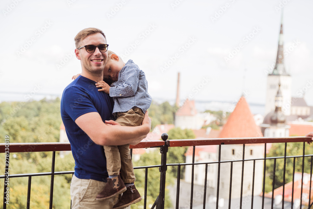The happy father holding his little son in arms against the background of the view on the city