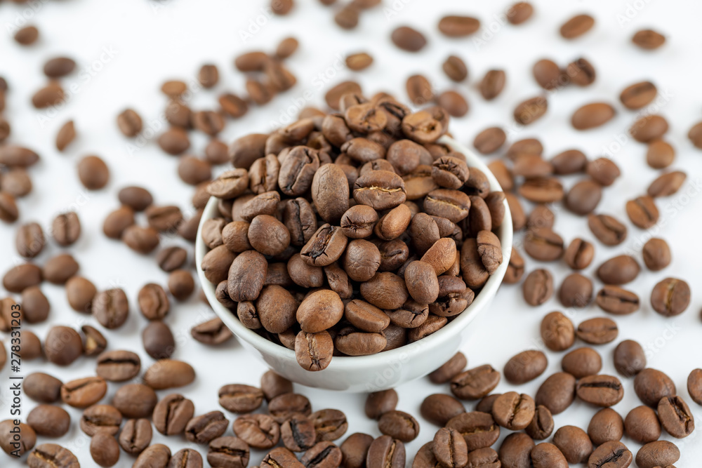 Roasted coffee beans in ceramic bowl on white, close-up Roasted coffee beans in ceramic bowl on white, close-up