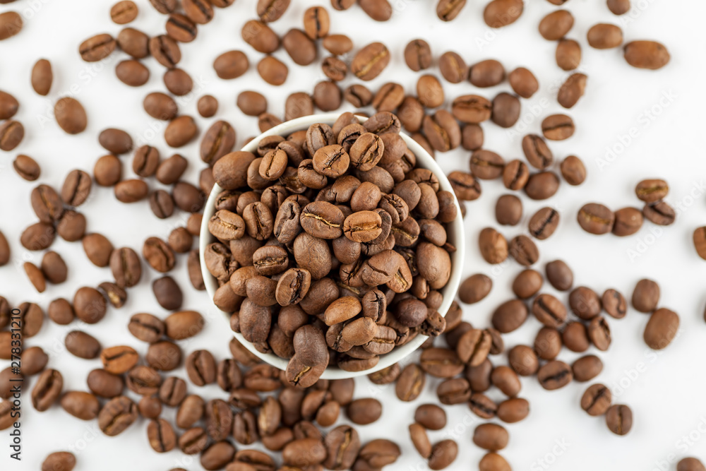 Roasted coffee beans in ceramic bowl on white, close-up, top view Roasted coffee beans in ceramic bowl on white, close-up, top view