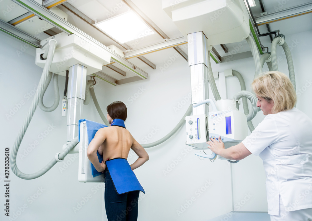 Radiologist and patient in a xray room. Classic ceilingmounted xray