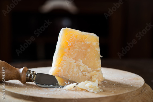 Aged Italian parmesan cheese peeled on wooden cutting board