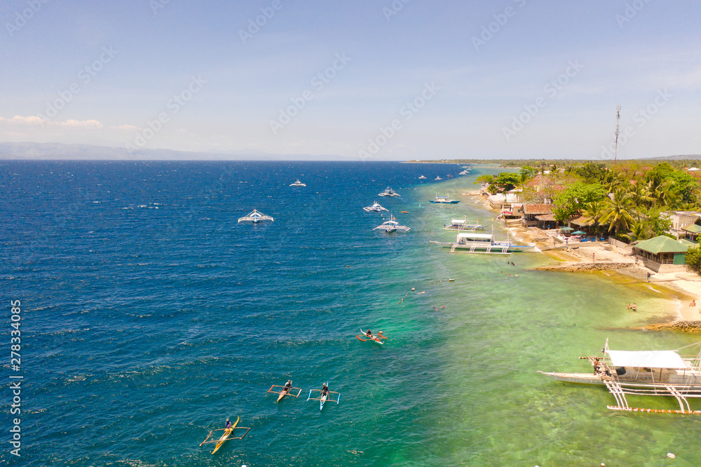 Coast of Cebu island, Moalboal, Philippines, top view. Boats near the shore in sunny weather. Seascape with coral reef near the shore.