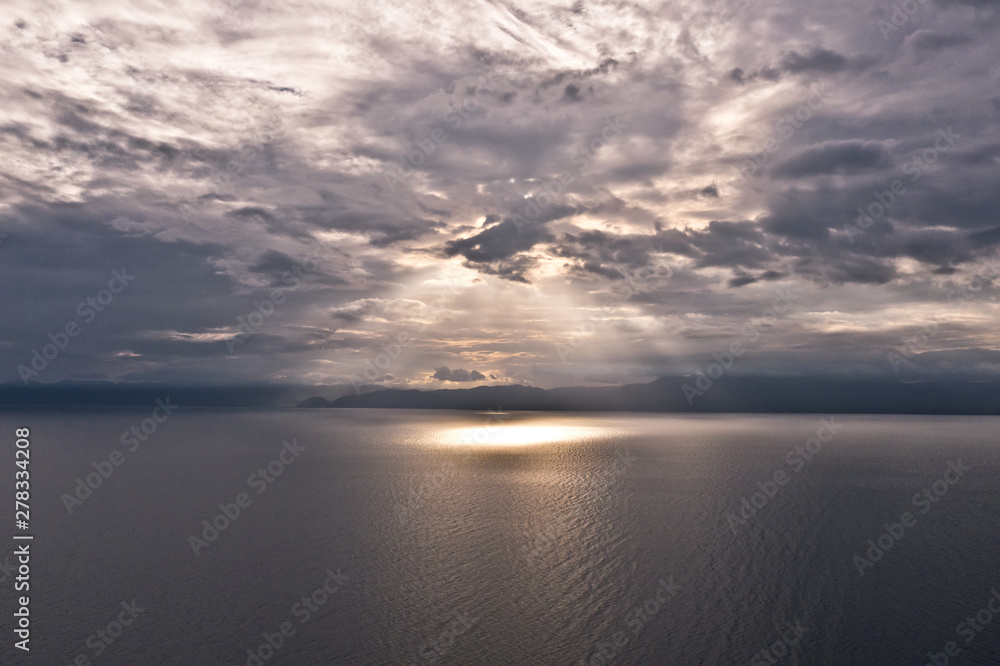 Clouds and rays of sun above the sea. Bright light with sun rays and heavy clouds above the sea. Seascape with dramatic sky.