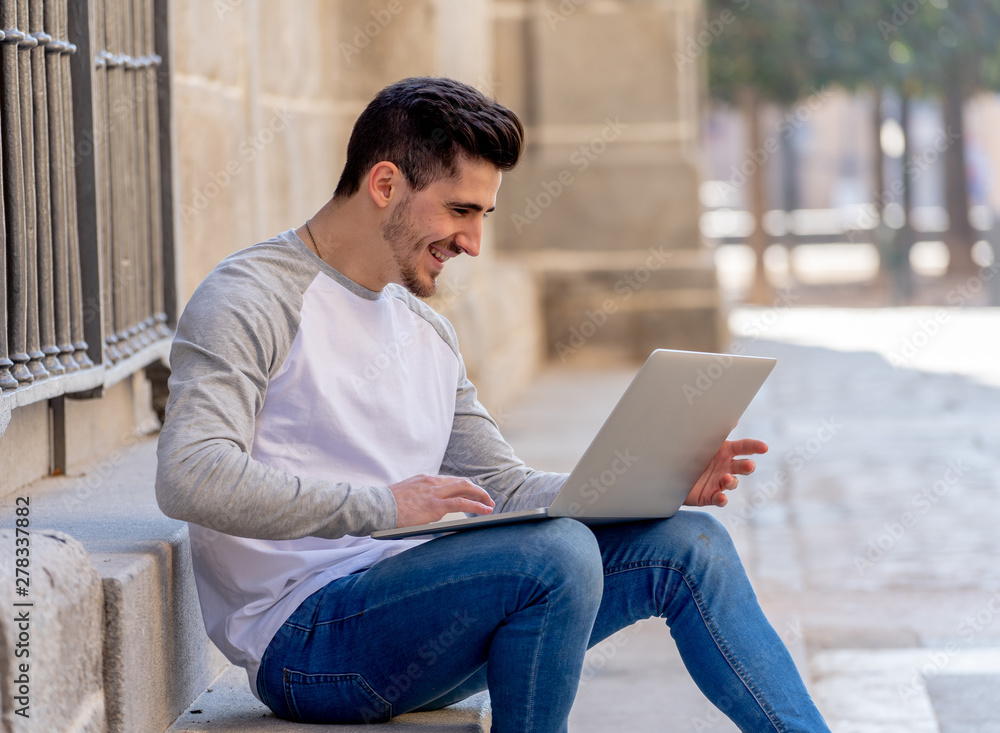 Young handsome man working and studying on laptop in a european Young handsome man working and studying on laptop in a european