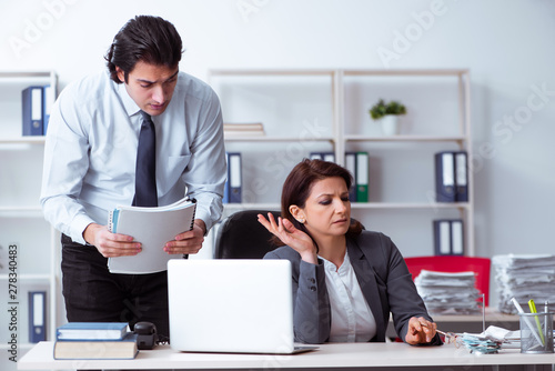 Old female boss and young male employee in the office  