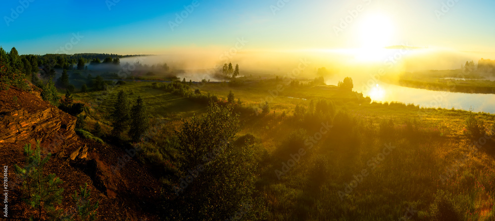 Fantastic foggy river with fresh green grass in sunlight. Sun beams over the river.. Dramatic colorful scenery. Ural, Russia - obrazy, fototapety, plakaty 