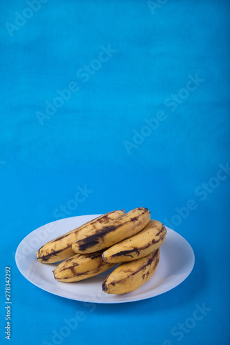 ugly bananas lie on a blue porcelain plate on a blue background. copy sraes photo