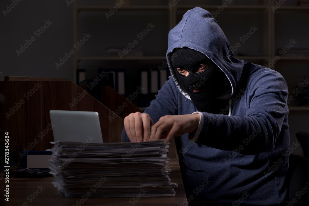 Male thief in balaclava in the office night time Male thief in balaclava in the office night time