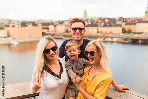 Portrait of the cheerful family who is standing against the background of the city and sea © Myroslava