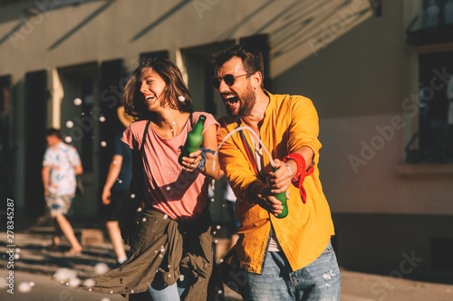 Young couple dancing on the street and holding two bottles of beer