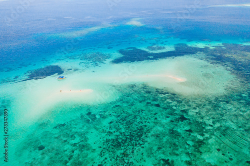 Coral reef with turquoise water and sandy shoals. Large atoll with beautiful lagoons. Tourists relax in the warm sea water. Tropical sea, view from above.