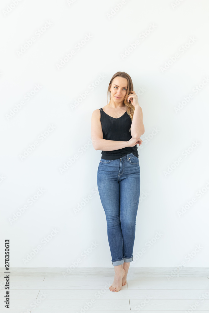 Style, people concept - young woman in jeans and black shirt standing over the white background Style, people concept - young woman in jeans and black shirt standing over the white background