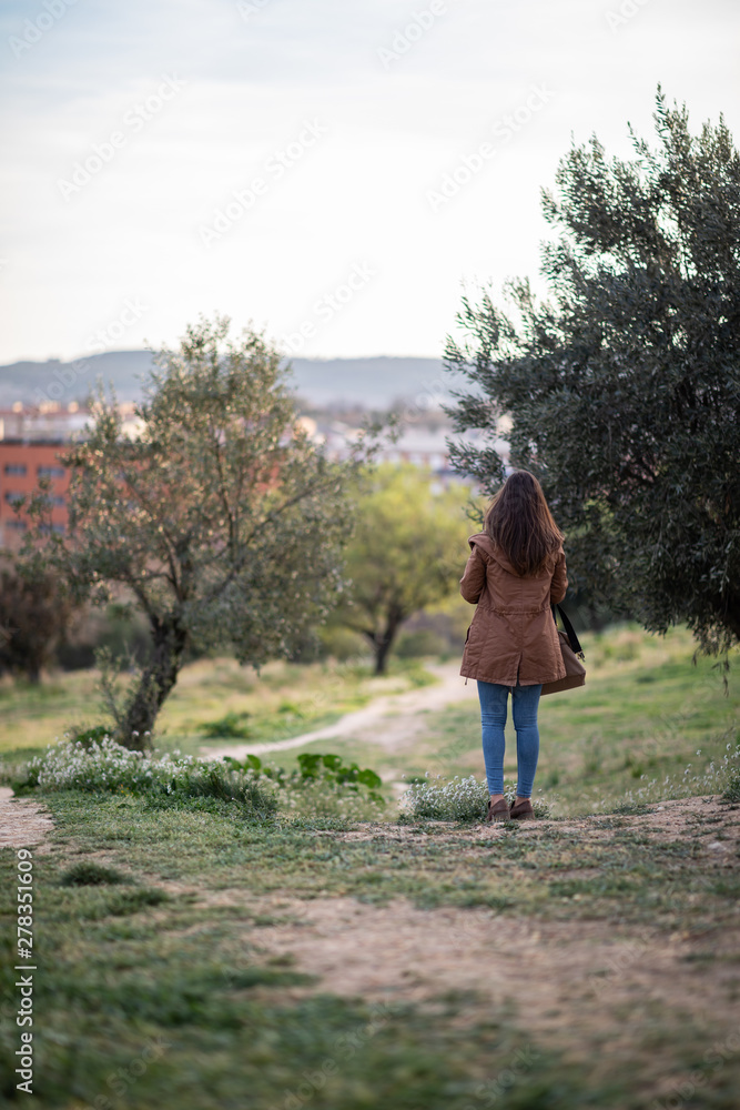 Beautiful woman standing on park during sunset Beautiful woman standing on park during sunset