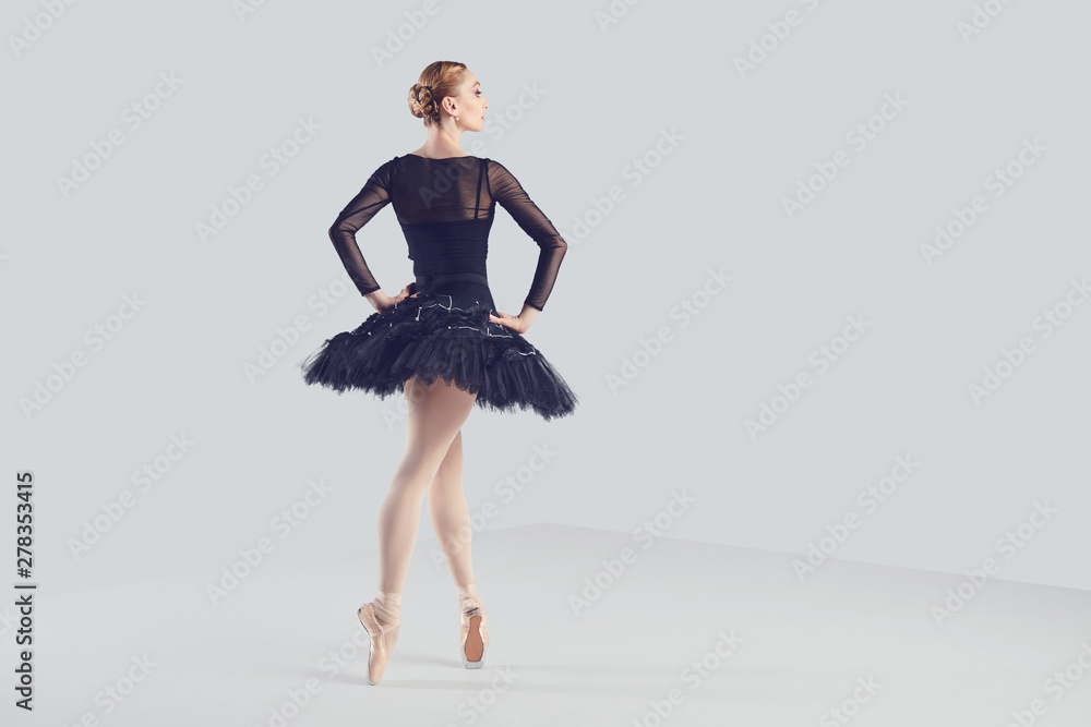 Ballerina in a black tutu elegantly dancing on a black background. Ballerina in a black tutu elegantly dancing on a black background.