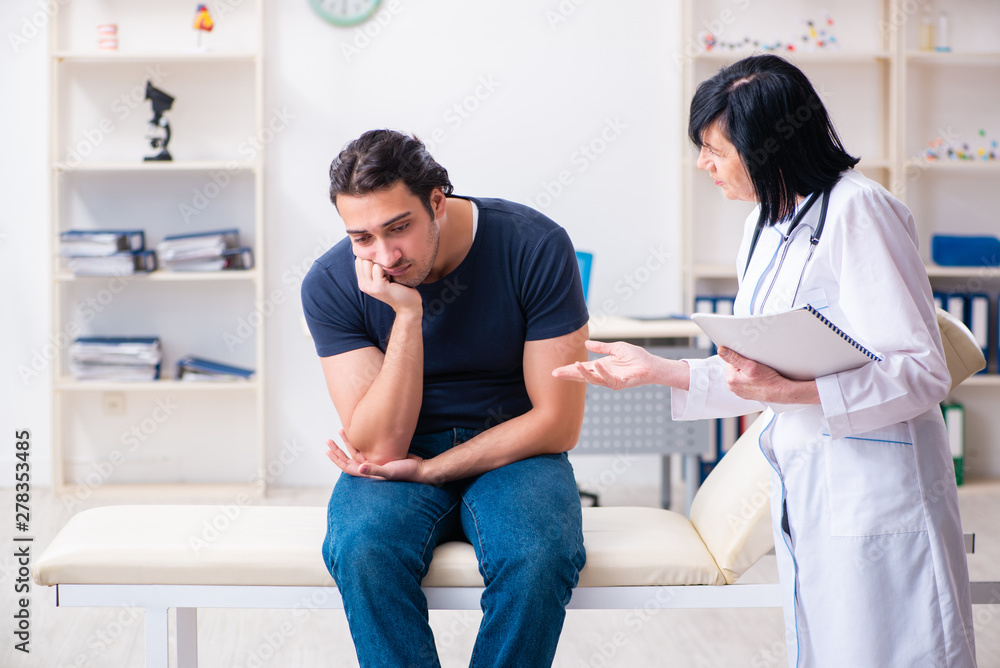 Young male patient visiting aged female doctor Young male patient visiting aged female doctor