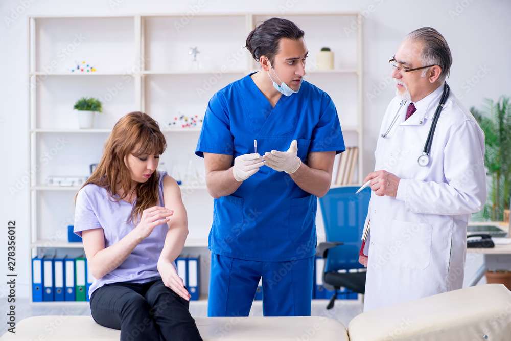 Fototapeta premium Two doctors examining young woman 