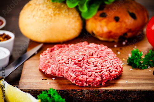 Fresh raw steaks on cutting board with vegetables