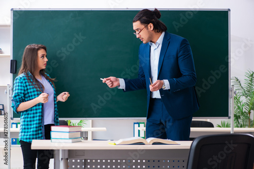 Young handsome teacher and female student in the classroom 