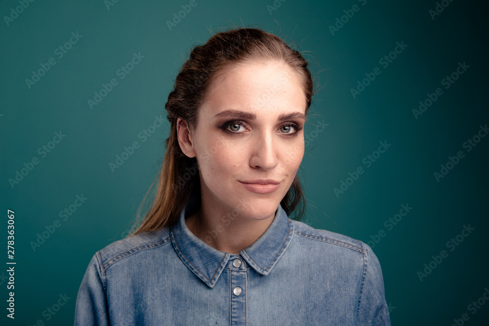 Fototapeta premium Closeup portrait of pretty young woman posing in a studio isolated over the blue background