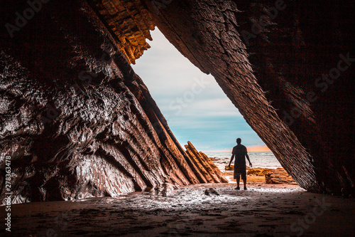 A young man exploring the beautiful natural cave that was used in the filming of game of thrones in the flysch of the Itzurun beach in Zumaia. Basque Country photo