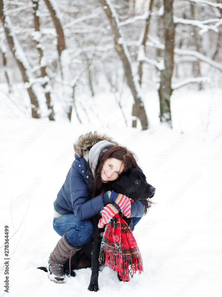 Fototapeta premium Beautiful young woman playing with her dog.Labrador retriever on a background of winter forest