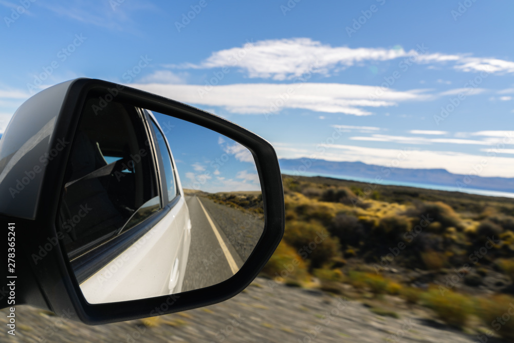 Look at side or rear mirror while driving on street in summer with golden plant leaves with sunshine blue sky