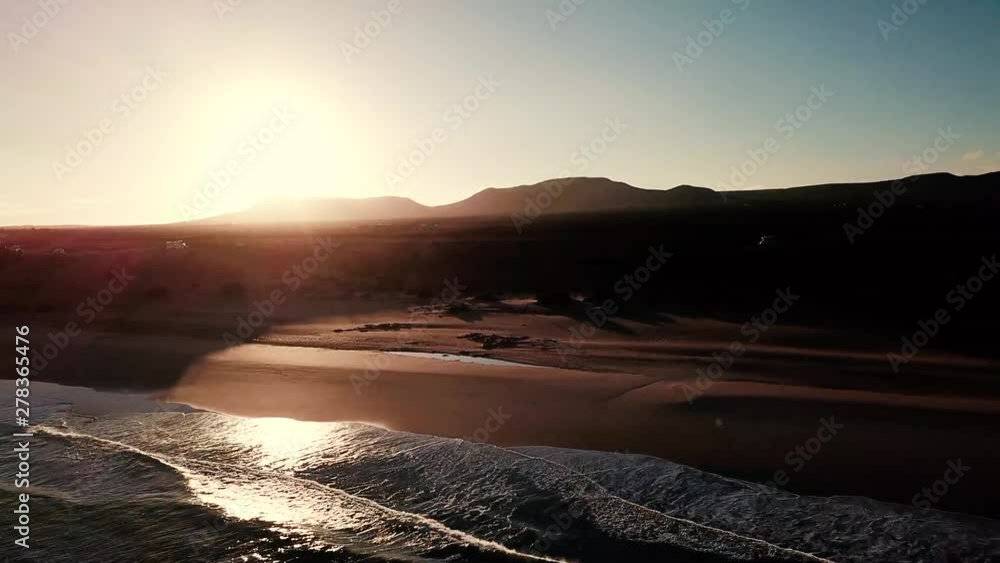 Beach and ocean during sunrise or sunset time with sun behind the mountains in background - beautiful aerial view of nature outdoors - nobody there and travel concept for wild coasts Beach and ocean during sunrise or sunset time with sun behind the mountains in background - beautiful aerial view of nature outdoors - nobody there and travel concept for wild coasts