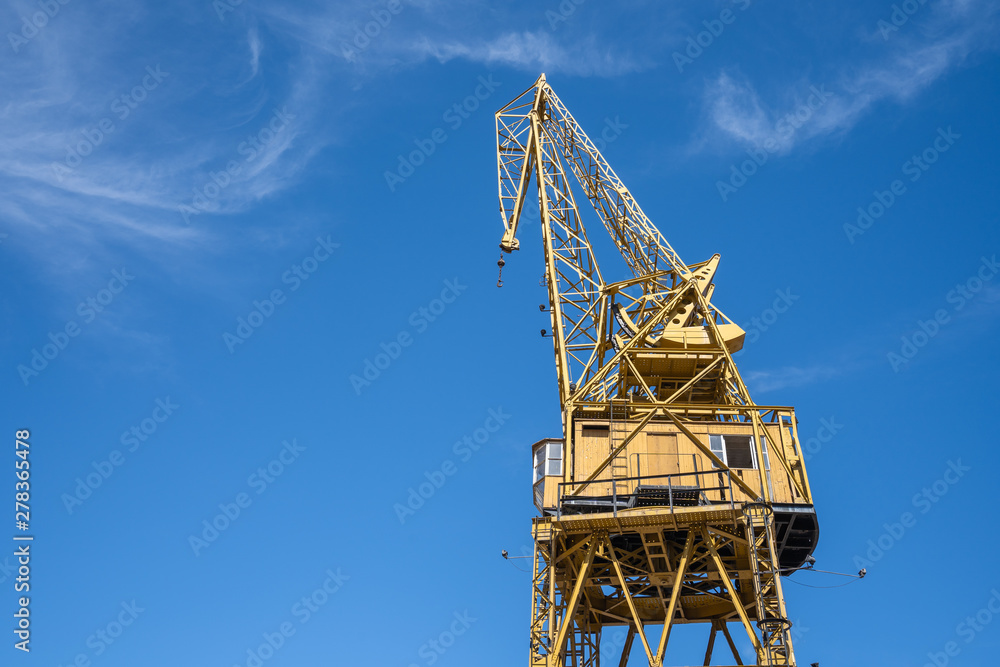 Tall yellow construction crane with clear blue sky, tool or machine to lifting huge and heavy for industrial development