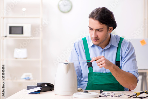 Obraz na plátně Young man repairing kettle in service centre