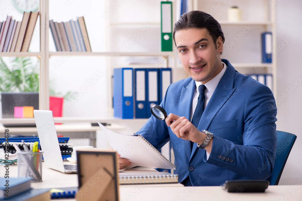 Young handsome employee in the office 